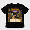 A black short-sleeve t-shirt with a large, colorful wizard-themed graphic on the front. The graphic features the text 'BOOK WEEK QUEST', 'WIZARD ACADEMY', and 'TAYLOR' above an illustration of a wizard with a magnifying glass, a castle, an owl, and a treasure chest.