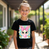 Young girl wearing a black t-shirt with a colorful bunny design outdoors.