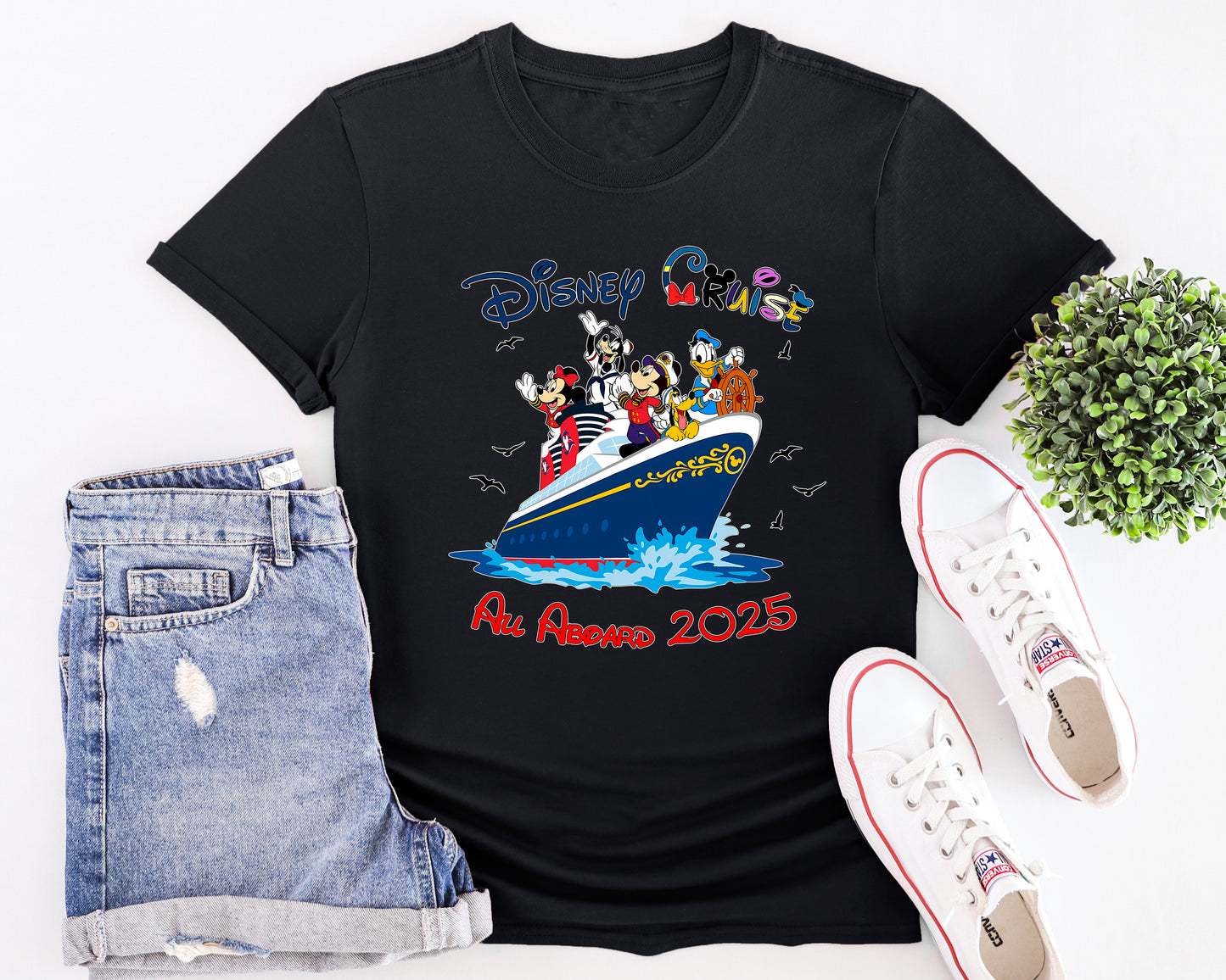 Black t-shirt with Disney design, denim shorts, and white sneakers on a white background