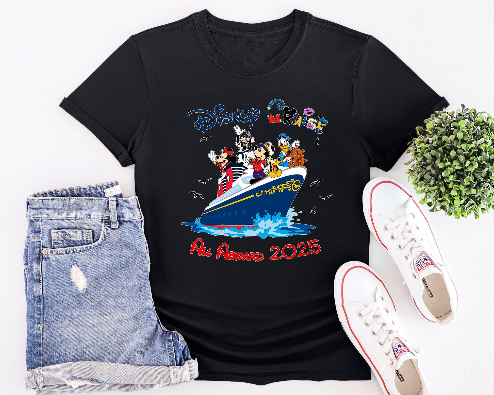 Black t-shirt with Disney design, denim shorts, and white sneakers on a white background