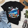 Black t-shirt with cruise ship graphic on a wooden surface with jeans, sneakers, and a phone.