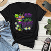 Black t-shirt with Mardi Gras Margaritas design on a wooden surface with jeans and sneakers.