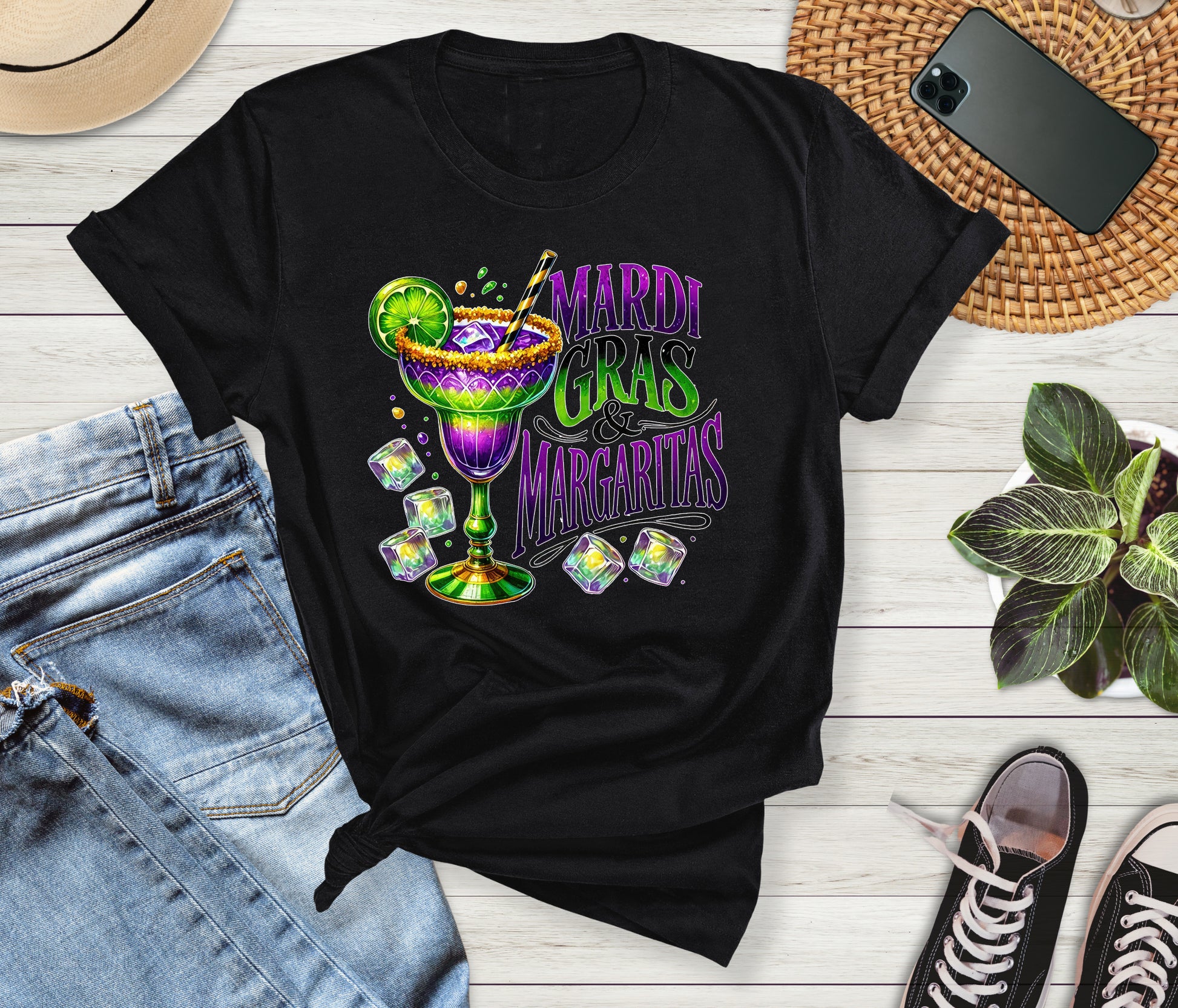 Black t-shirt with Mardi Gras Margaritas design on a wooden surface with jeans and sneakers.