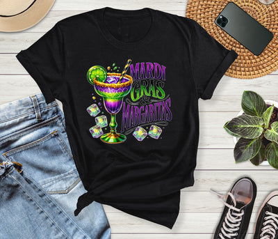 Black t-shirt with Mardi Gras Margaritas design on a wooden surface with jeans and sneakers.