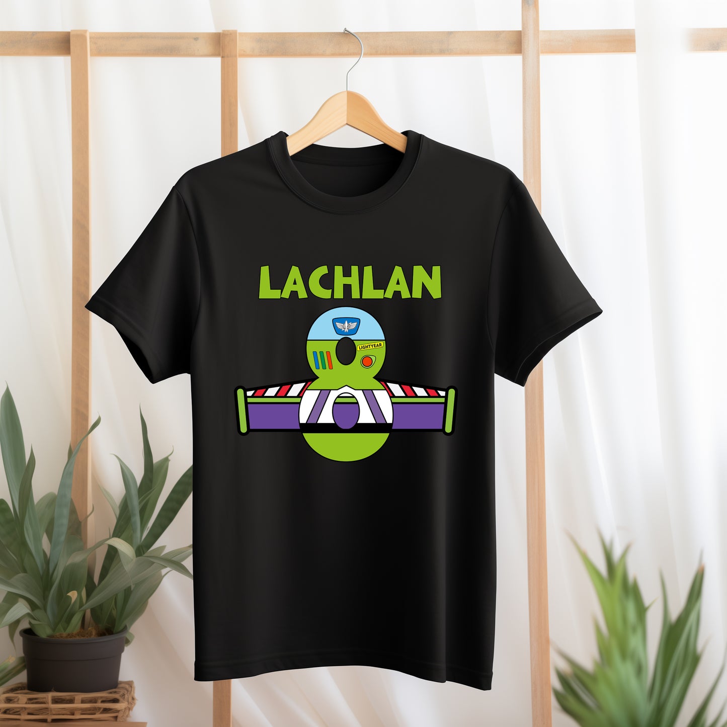 Black t-shirt with 'LACHLAN' and graphic design on a hanger against a light background