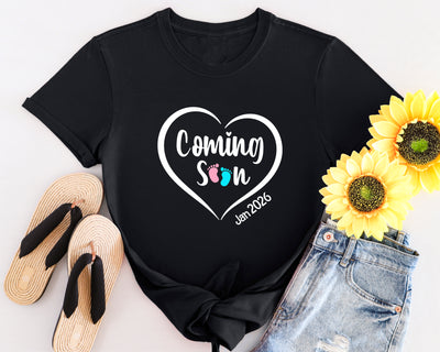 White maternity t-shirt with “Coming Soon” text and baby footprints graphic, ideal for pregnancy announcements.