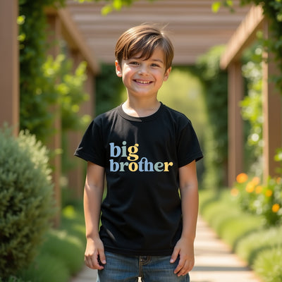 Child wearing a 'big brother' shirt standing outdoors with greenery in the background