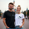 Man and woman standing together in front of a castle with matching t-shirts.