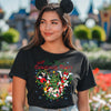 Person wearing a black t-shirt with Christmas design and Mickey Mouse ears in a theme park setting.
