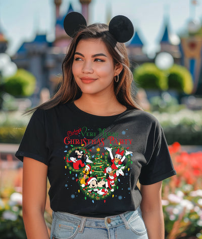 Person wearing a black t-shirt with Christmas design and Mickey Mouse ears in a theme park setting.