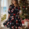 Woman in a festive dress standing in front of a decorated Christmas tree with ocean view.