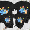 Four black t-shirts with colorful birthday designs on a wooden surface.