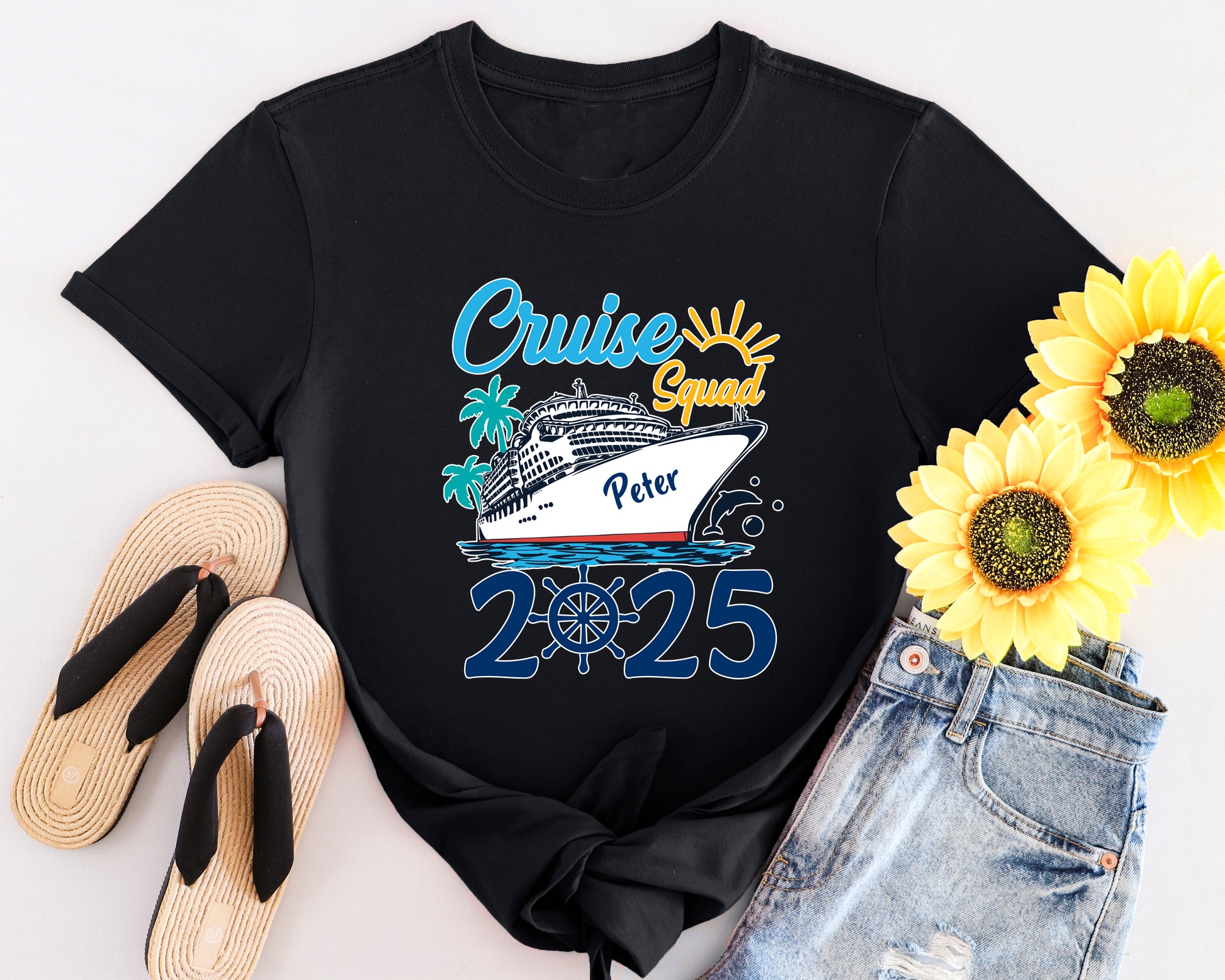 Black t-shirt with 'Cruise Squad 2025' design, sunflowers, flip-flops, and denim shorts on a white background