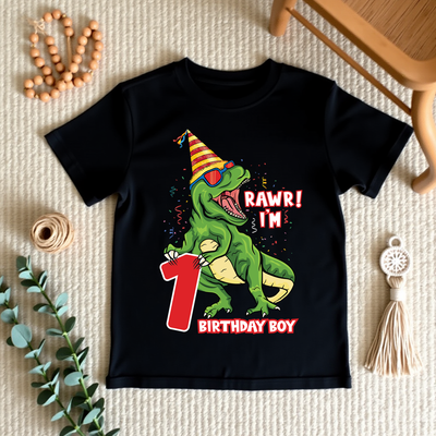 Black t-shirt with a dinosaur design celebrating a first birthday on a textured surface.