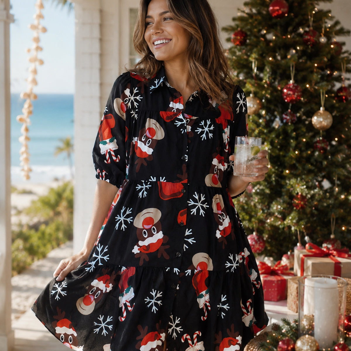 Woman in a festive dress with Christmas patterns standing in front of a decorated tree.
