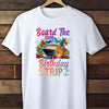 White t-shirt with a colorful graphic and text 'Board The Ship It's Birthday Trip' on a wooden background