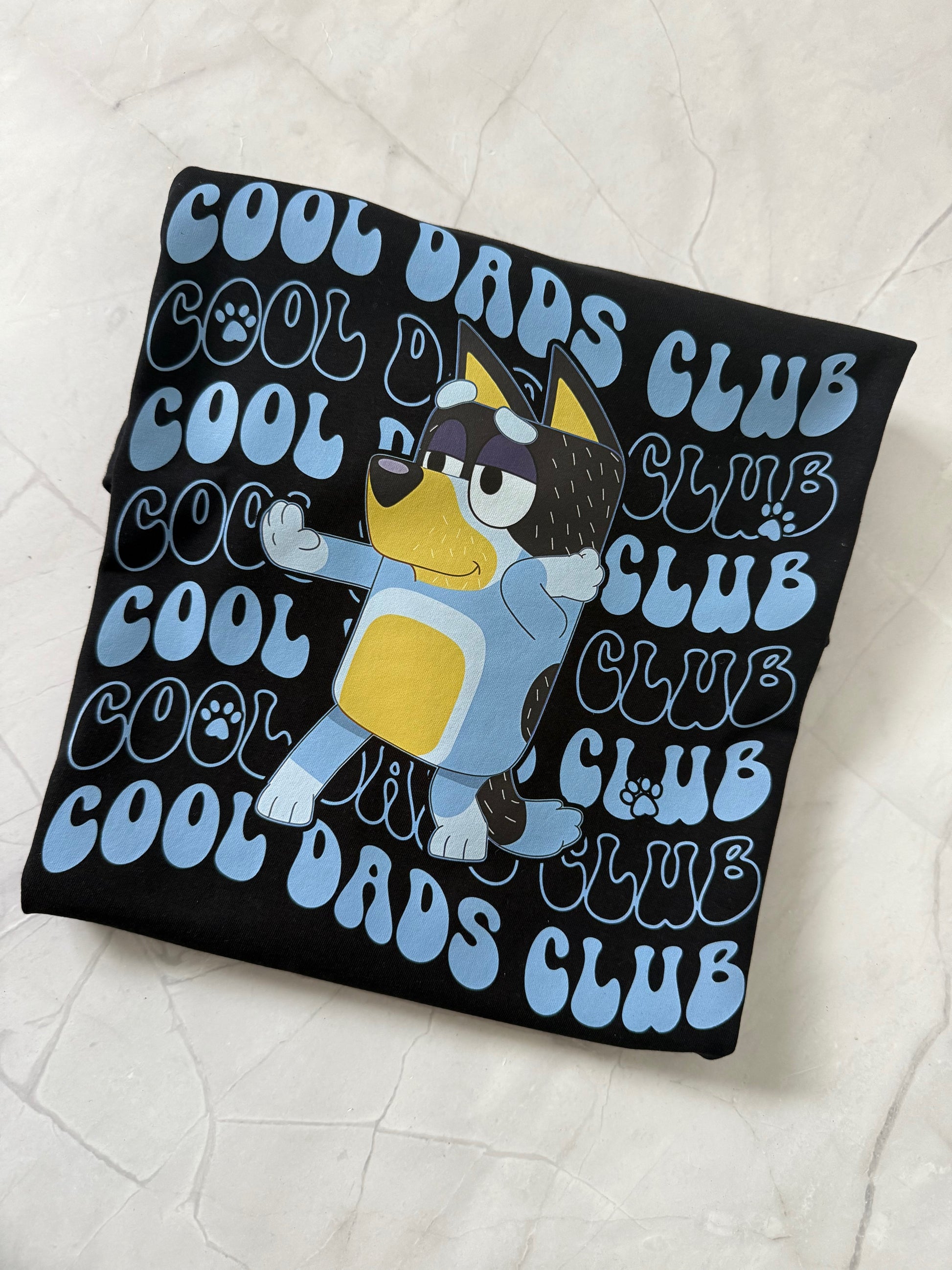 Tshirt with cartoon penguin design and 'Cool Dads Club' text on a white background