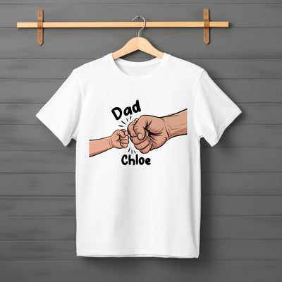 Flat lay of “Fist Pump Dad” t-shirt featuring bold lettering and illustrated fist graphic.