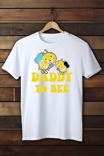 White t-shirt with bee graphics and 'Daddy to Bee' text on a wooden background