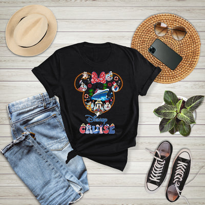 Black t-shirt with Disney Cruise design on a wooden surface with jeans, sneakers, hat, and phone.