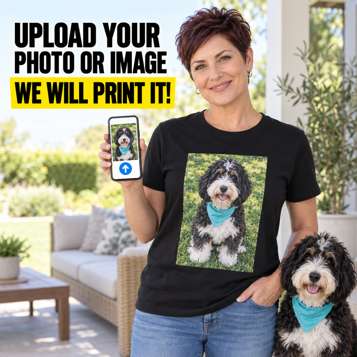 A woman stands outdoors holding up a smartphone showing a custom pet photo, with a black graphic T-shirt featuring a printed dog portrait on the front. A real dog sits beside her on a patio with furniture and plants in the background.