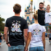 Two people wearing matching t-shirts with a castle design and 'Happy Ever After' text, standing in front of a Disney castle.