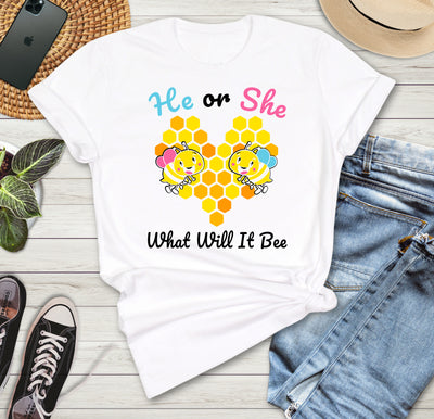 White t-shirt with 'He or She What Will It Bee' design on a wooden surface with jeans, sneakers, and a phone.