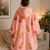 Person wearing a pink hoodie with ice cream pattern in a living room.