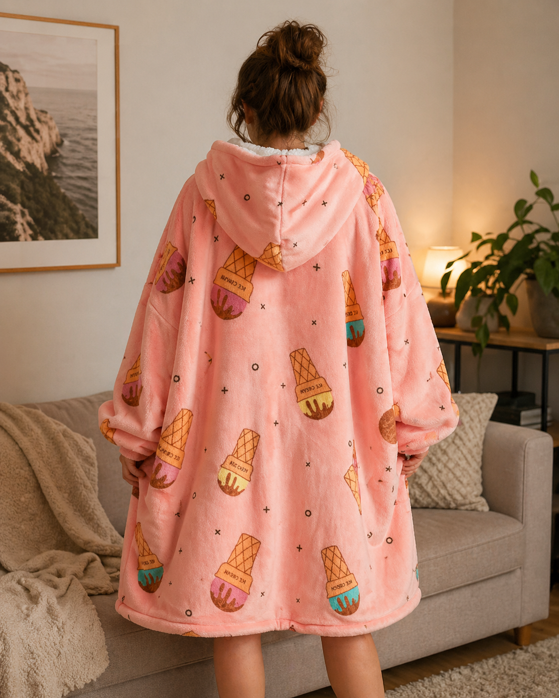 Person wearing a pink hoodie with ice cream pattern in a living room.