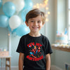 Child wearing a 'It's My Birthday' shirt with Spider-Man graphic, standing in a room with balloons and a cake.
