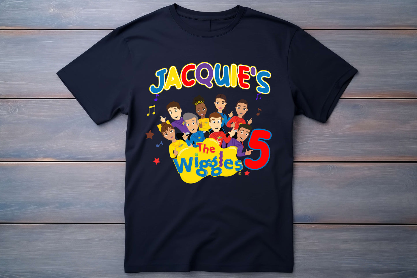 Black t-shirt with 'The Wiggles' design and text on a wooden background