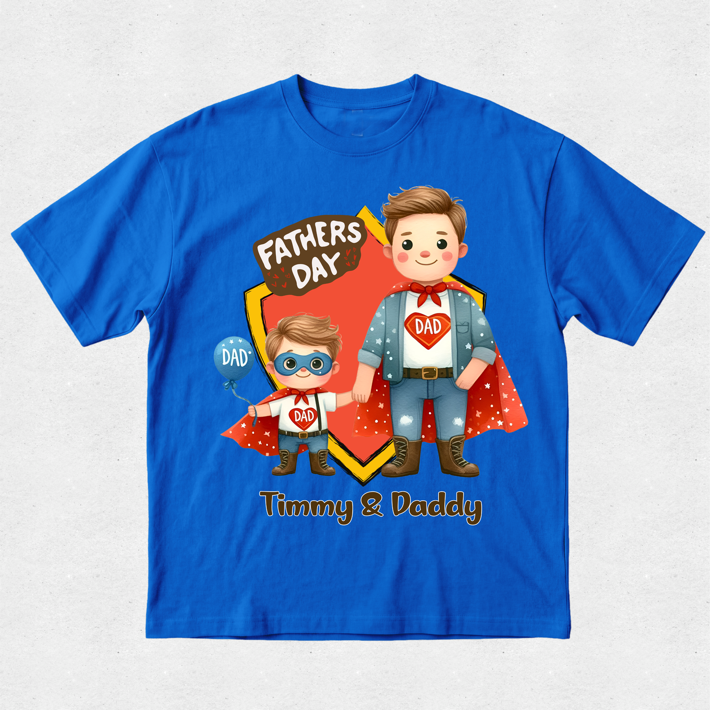 A royal blue short-sleeve t-shirt with a colorful graphic on the front featuring two cartoon superheroes labeled 'Fathers Day' and 'Timmy & Daddy'.