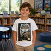 A smiling young boy stands in a bright children's library wearing a white T-shirt with a large printed cover of 'The Brave Knight' book on the front, paired with khaki pants.