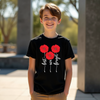 Child wearing a black t-shirt with red floral design and text outdoors