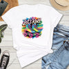 White t-shirt with colorful roller skates graphic and 'Let's Roll' text on a wooden surface with jeans and sneakers.