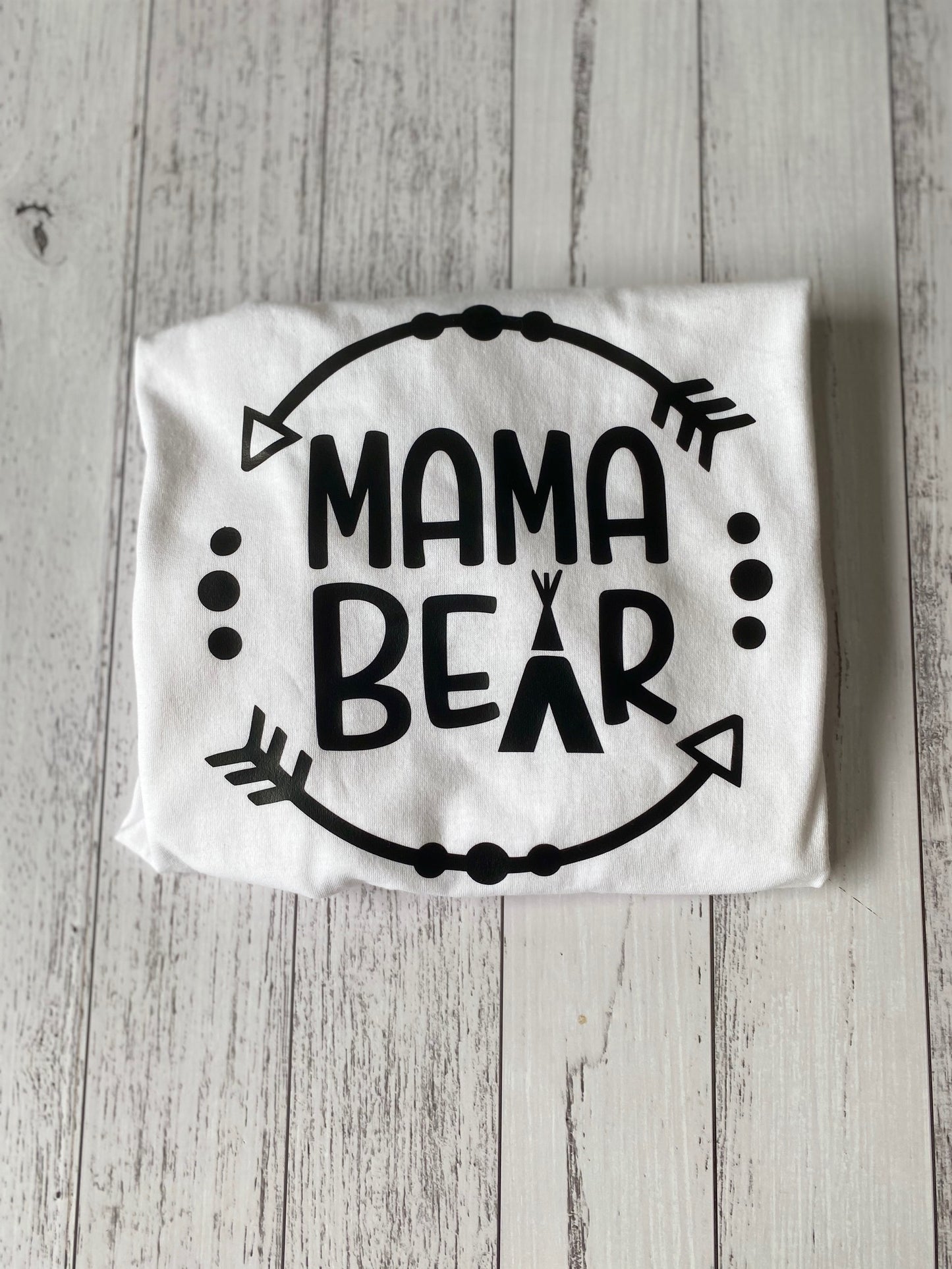 White shirt with 'Mama Bear' text on a wooden surface