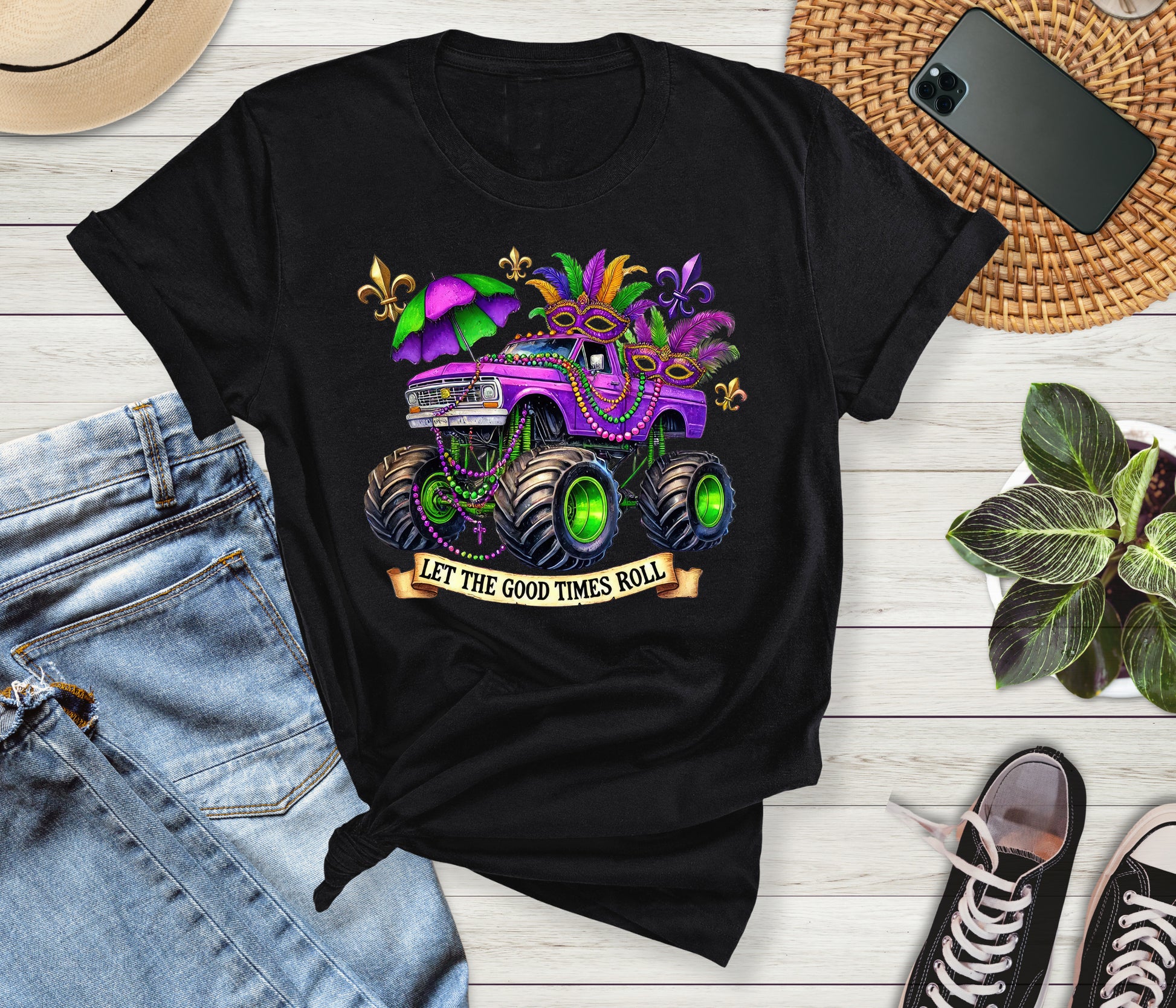Black t-shirt with a colorful graphic and text 'Let the good times roll' on a wooden surface with jeans and sneakers.