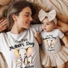 Woman and baby wearing matching 'Our First Mother's Day Together' shirts and outfits.