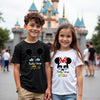 Two children wearing matching t-shirts with a disney castle in the background