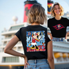 Person wearing a black t-shirt with a colorful graphic design in front of a cruise ship.