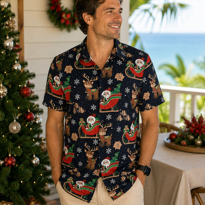 Man wearing a festive patterned shirt with Christmas-themed designs, standing in front of a decorated Christmas tree.