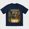 A navy blue short-sleeve t-shirt with a detailed graphic print on the front. The graphic features a medieval knight in blue armor on a white horse, surrounded by a castle, scrolls, and banners reading 'BOOK WEEK QUEST', 'KNIGHT'S CASTLE', and 'ROBBIE'.