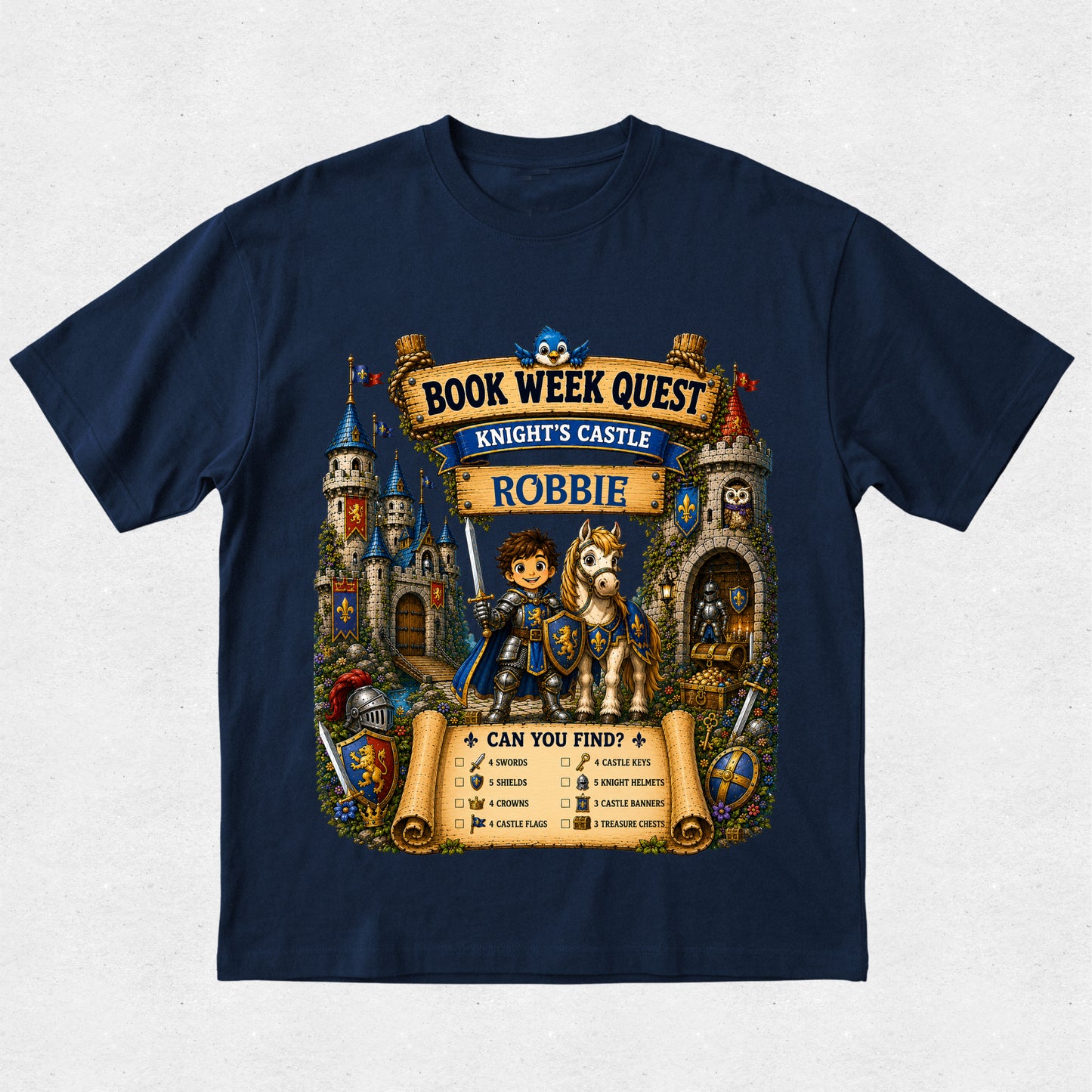 A navy blue short-sleeve t-shirt with a detailed graphic print on the front. The graphic features a medieval knight in blue armor on a white horse, surrounded by a castle, scrolls, and banners reading 'BOOK WEEK QUEST', 'KNIGHT'S CASTLE', and 'ROBBIE'.