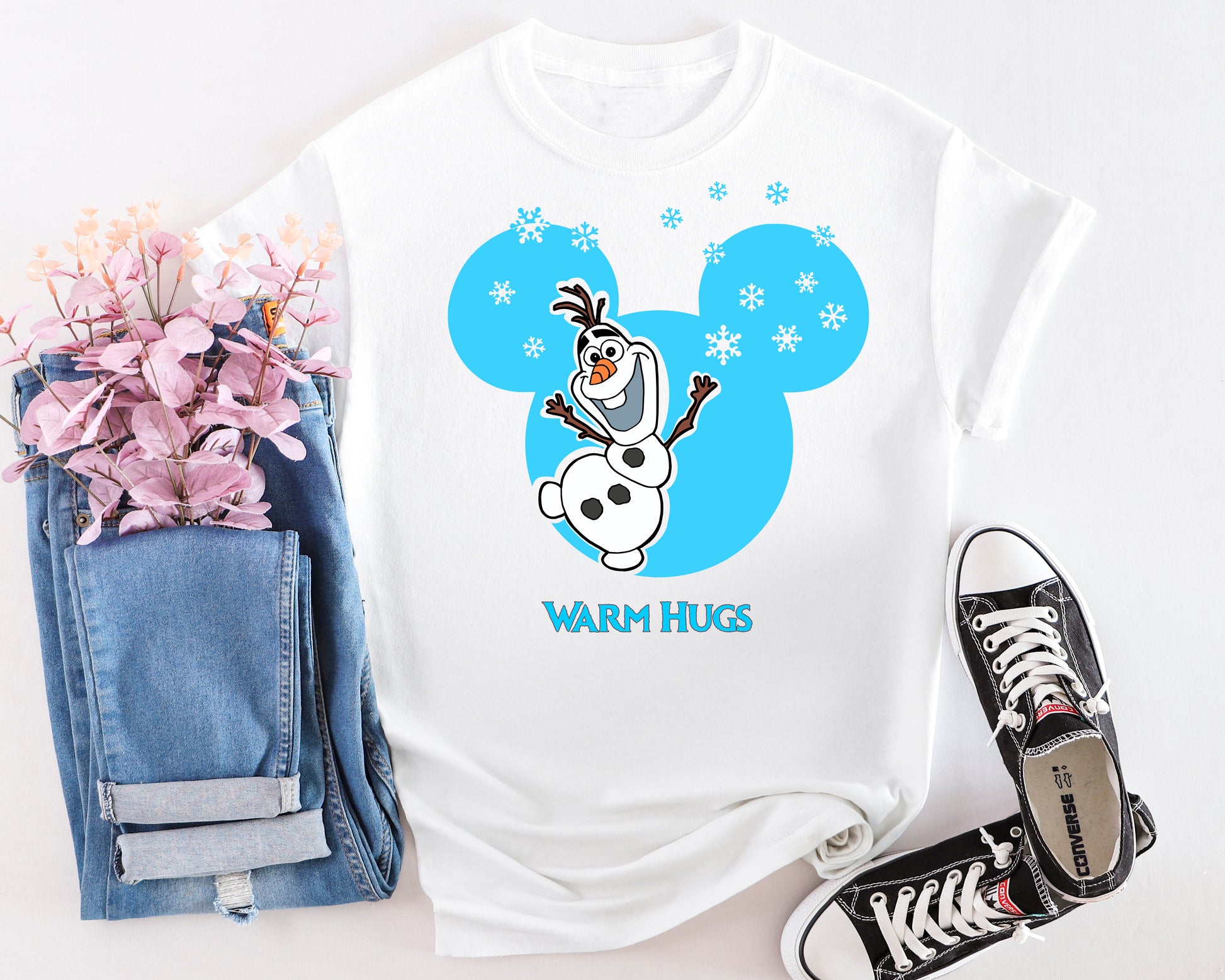 White t-shirt with cartoon character design, jeans, and sneakers on a white background