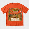 An orange short-sleeve crewneck t-shirt featuring a large, colorful graphic print on the front with the text 'BOOK WEEK QUEST OUTBACK ADVENTURE' and 'from the writing of Nathaniel'. The graphic depicts an adventurous safari scene with a child, a jeep, a kangaroo, a koala, a bird, and a checklist at the bottom.