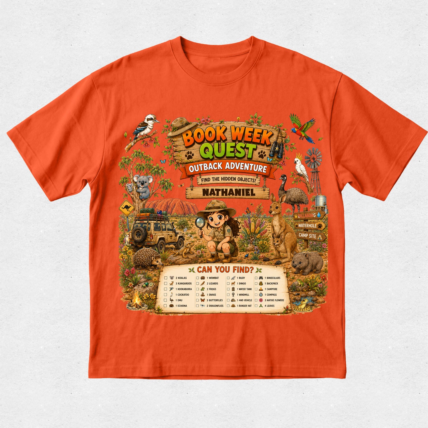 An orange short-sleeve crewneck t-shirt featuring a large, colorful graphic print on the front with the text 'BOOK WEEK QUEST OUTBACK ADVENTURE' and 'from the writing of Nathaniel'. The graphic depicts an adventurous safari scene with a child, a jeep, a kangaroo, a koala, a bird, and a checklist at the bottom.