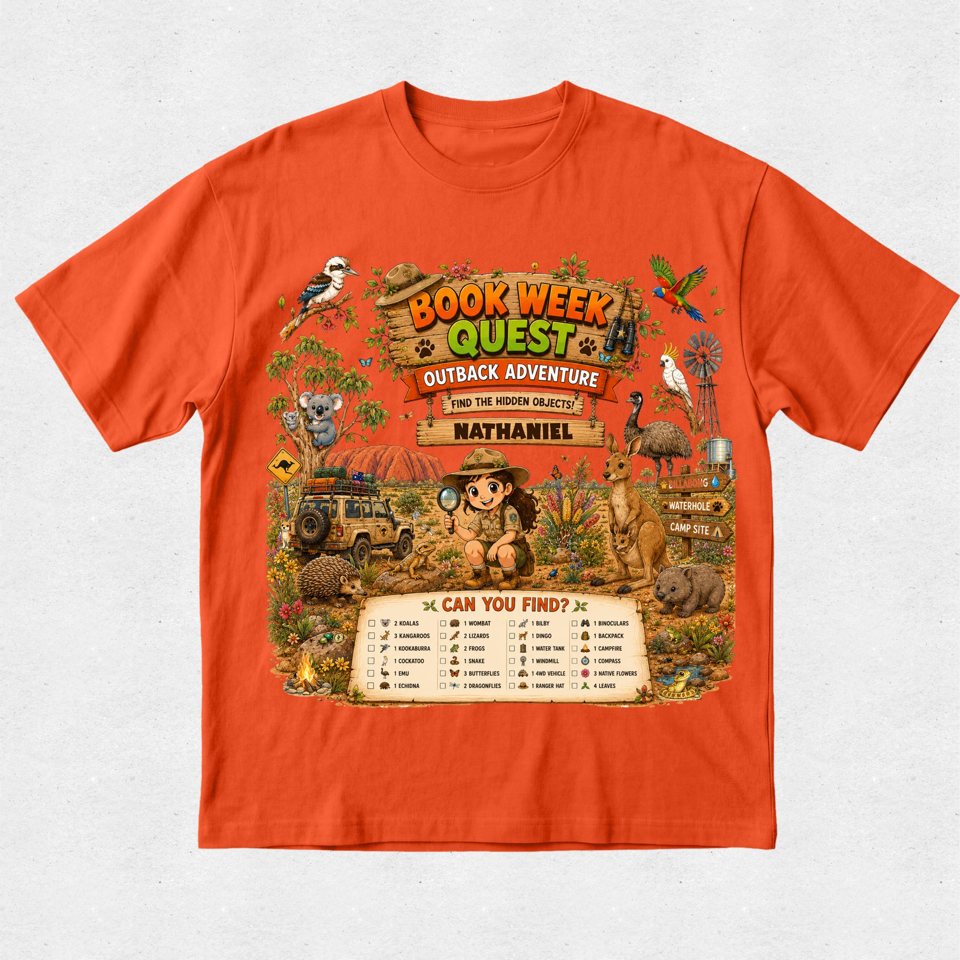 An orange short-sleeve crewneck t-shirt featuring a large, colorful graphic print on the front with the text 'BOOK WEEK QUEST OUTBACK ADVENTURE' and 'from the writing of Nathaniel'. The graphic depicts an adventurous safari scene with a child, a jeep, a kangaroo, a koala, a bird, and a checklist at the bottom.