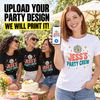 A woman outdoors holds up a smartphone showing a custom party design mockup on a white T-shirt, while three women in black T-shirts sit behind her at a party table. Large text at the top reads, 'UPLOAD YOUR PARTY DESIGN WE WILL PRINT IT!'.