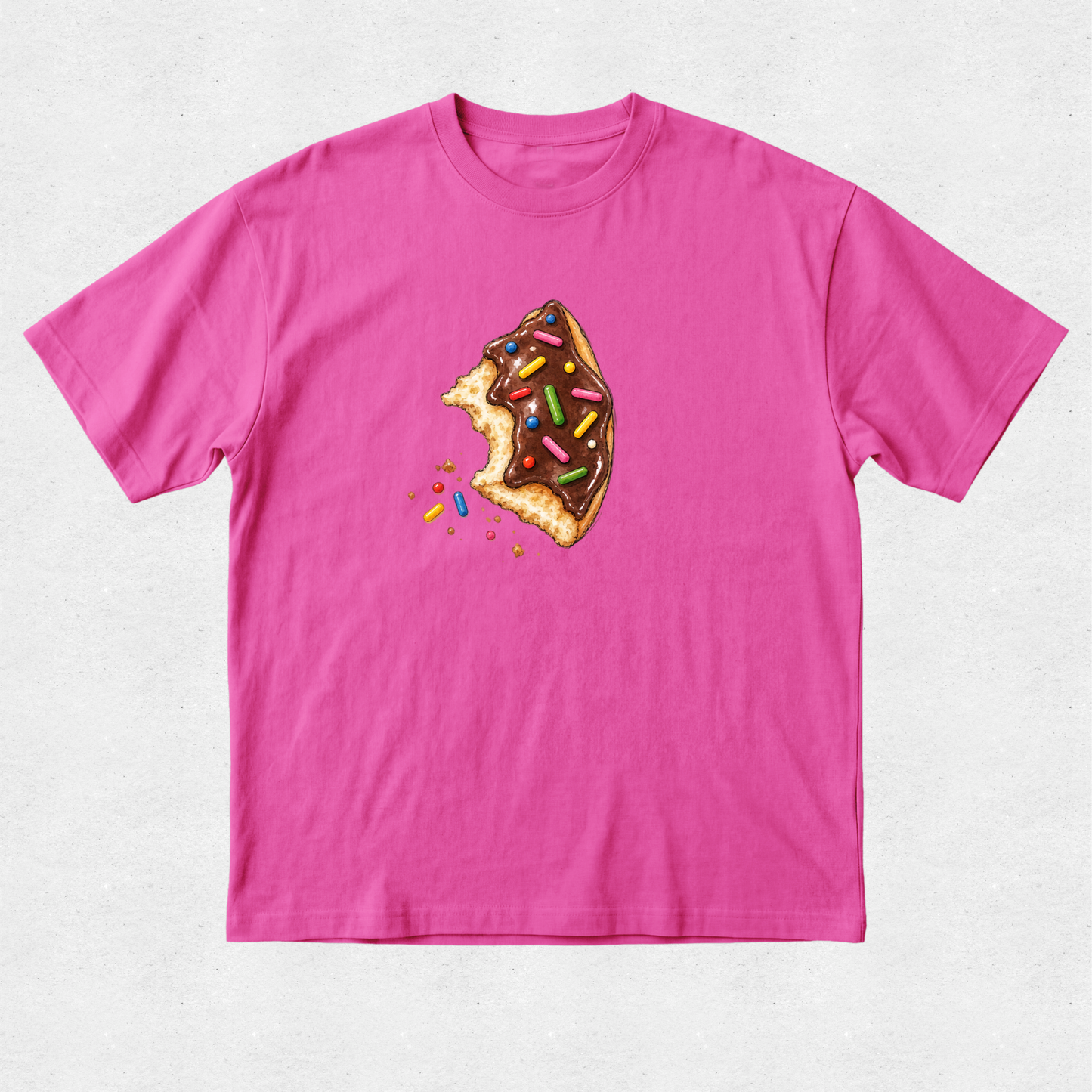 A bright pink short-sleeve crewneck t-shirt featuring a graphic of a partially eaten chocolate donut with colorful sprinkles on the chest, displayed flat against a light gray textured background.