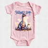A light pink short-sleeve baby bodysuit with a 'Father's Day 2026' graphic featuring two blue and purple dinosaurs on a textured off-white background.